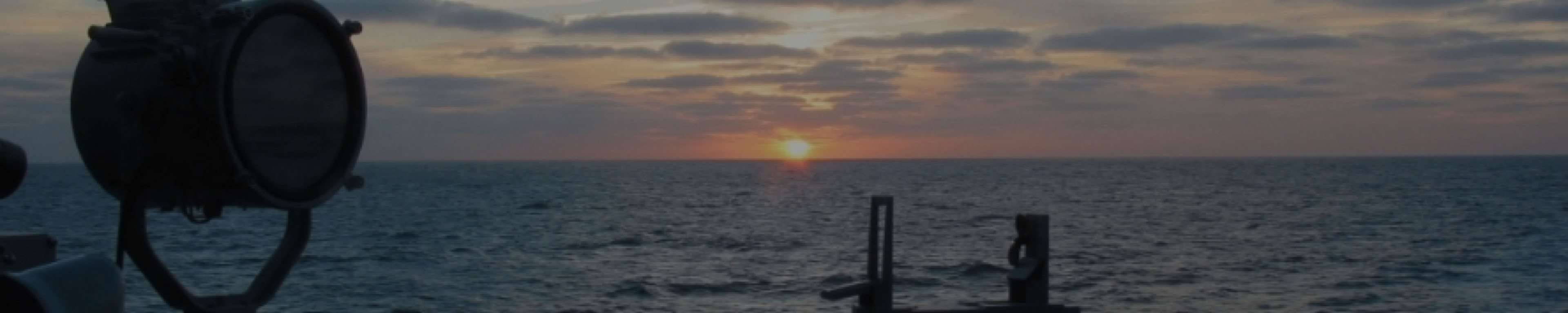 Zonsondergang op zee, gezien vanaf een M-Fregat met kompas en seinlamp op de voorgrond.